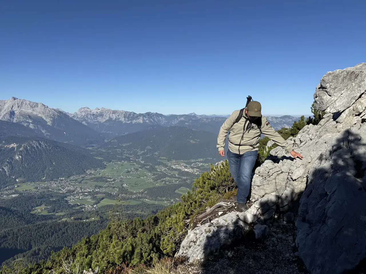 Jeroen op een rotsige bergkam tijdens een wandeling, met een dal en bergen achter hem.